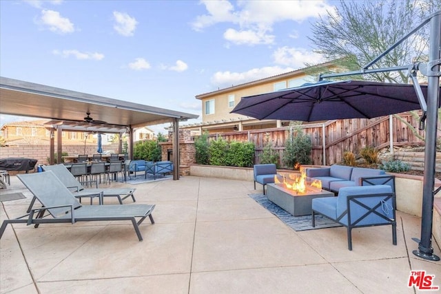 view of patio with ceiling fan, area for grilling, and an outdoor living space with a fire pit