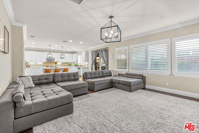 living room with hardwood / wood-style flooring, crown molding, and an inviting chandelier