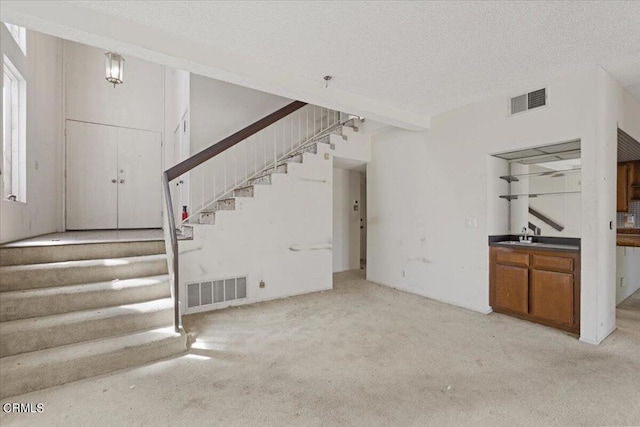 unfurnished living room featuring a textured ceiling and light carpet