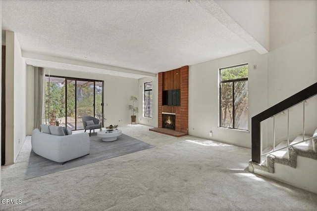 unfurnished living room featuring a brick fireplace, a textured ceiling, and carpet flooring