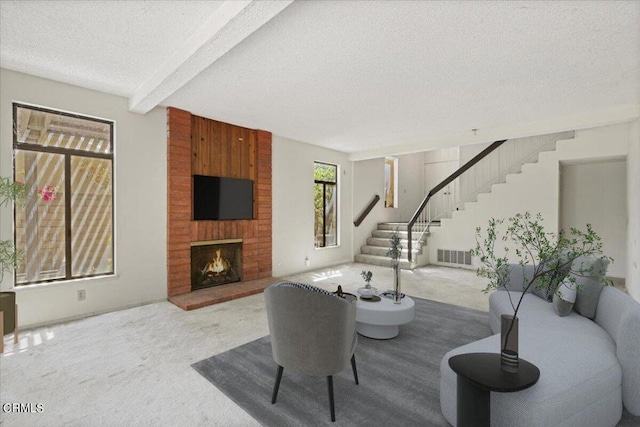 carpeted living room with a textured ceiling, a fireplace, and beam ceiling