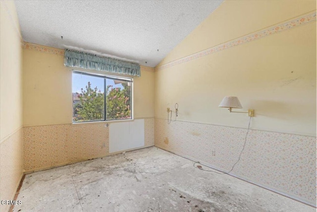 empty room featuring a textured ceiling and lofted ceiling