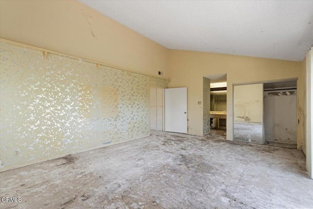 unfurnished bedroom featuring vaulted ceiling, a closet, and ensuite bathroom