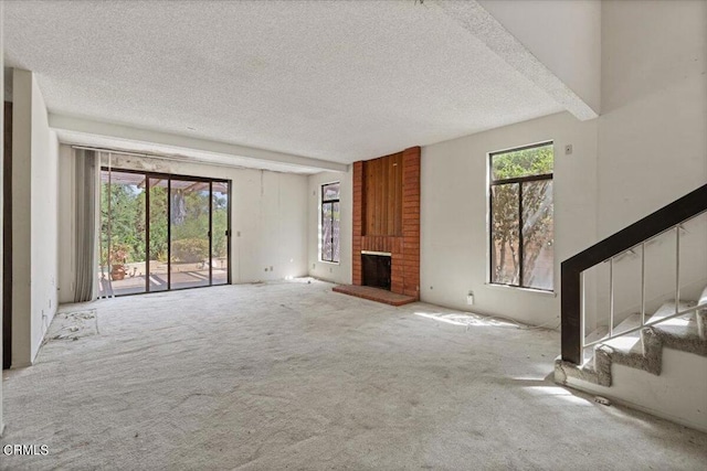 unfurnished living room featuring a brick fireplace, a textured ceiling, and carpet