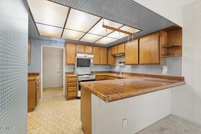 kitchen featuring tile counters, tasteful backsplash, sink, kitchen peninsula, and white range