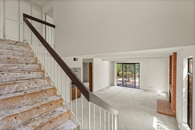 staircase featuring carpet floors and a towering ceiling