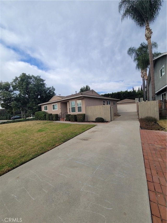 ranch-style home with a garage, a front lawn, and an outdoor structure