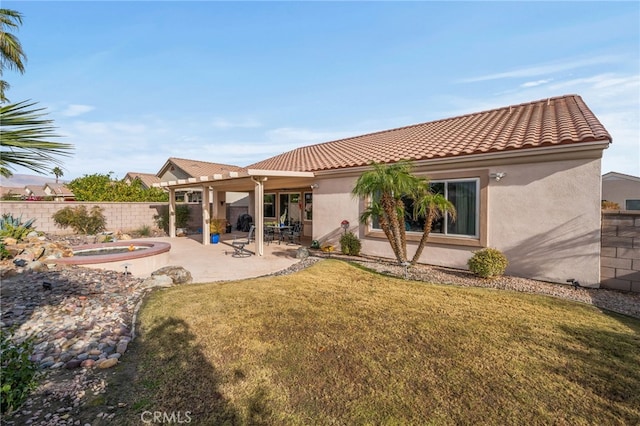 back of property with a patio, an outdoor hot tub, and a lawn