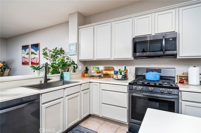 kitchen featuring white cabinetry, appliances with stainless steel finishes, sink, and light tile patterned floors