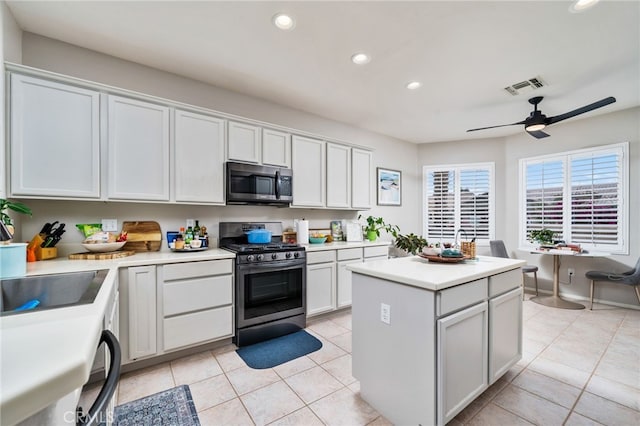 kitchen with light tile patterned floors, ceiling fan, white cabinetry, stainless steel appliances, and a center island