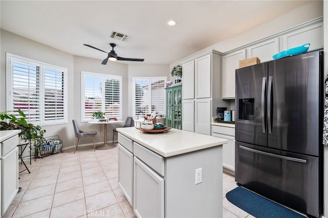 kitchen featuring white cabinetry, a center island, light tile patterned floors, ceiling fan, and fridge with ice dispenser