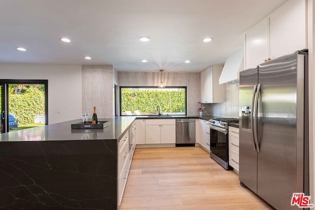 kitchen featuring a healthy amount of sunlight, white cabinets, stainless steel appliances, and custom range hood