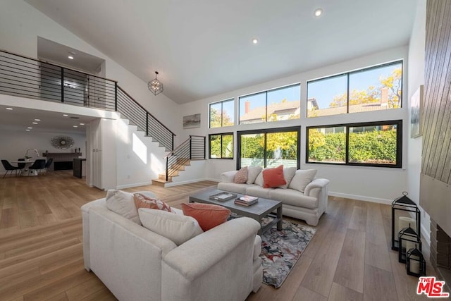 living room featuring high vaulted ceiling and light hardwood / wood-style flooring