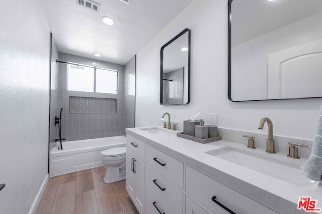 full bathroom with toilet, vanity, hardwood / wood-style floors, shower / bathtub combination, and a textured ceiling