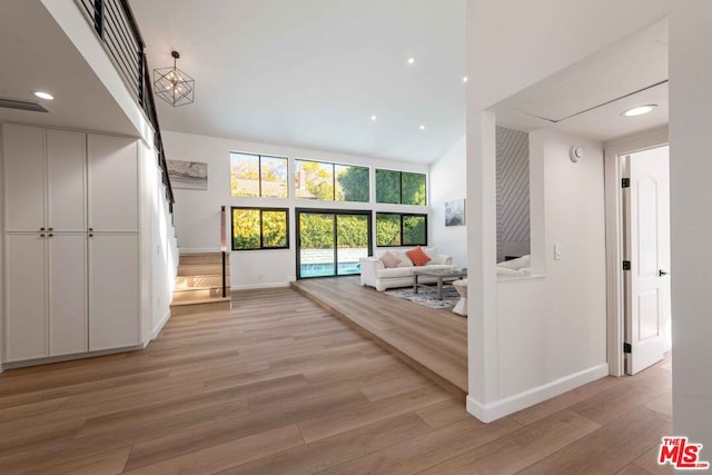 corridor featuring light wood-type flooring and a high ceiling