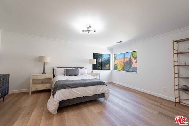 bedroom featuring ornamental molding and light hardwood / wood-style flooring