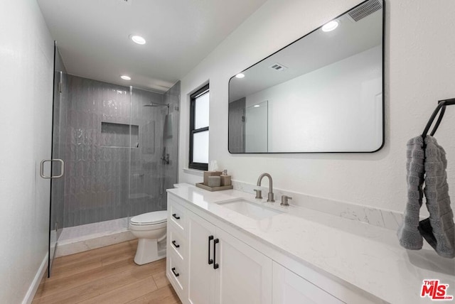 bathroom with toilet, walk in shower, hardwood / wood-style floors, and vanity