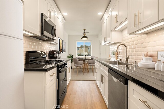 kitchen featuring decorative light fixtures, light hardwood / wood-style floors, sink, stainless steel appliances, and white cabinets