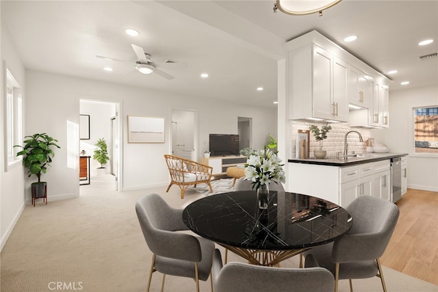 dining area with ceiling fan, light hardwood / wood-style flooring, and sink