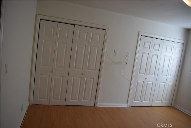 1718 Puente Ave Unit 40, Baldwin Park, CA 91706 - unfurnished bedroom featuring light wood finished floors, baseboards, and two closets