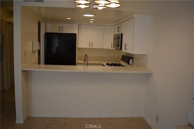 1718 Puente Ave Unit 40, Baldwin Park, CA 91706 - kitchen with black fridge, stove, stainless steel microwave, light countertops, and light tile patterned floors