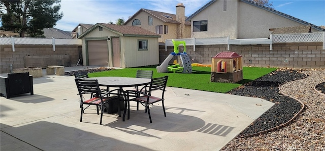 view of patio with a playground, a fire pit, and a storage unit