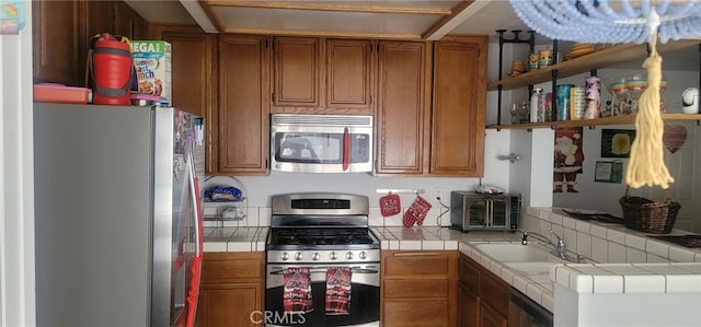 kitchen with sink, stainless steel appliances, tile countertops, and tasteful backsplash