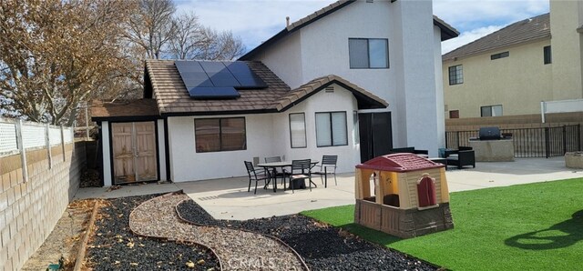 rear view of house featuring a lawn, a patio area, and solar panels