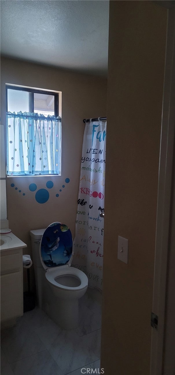 bathroom with toilet, vanity, tile patterned flooring, and a shower with shower curtain