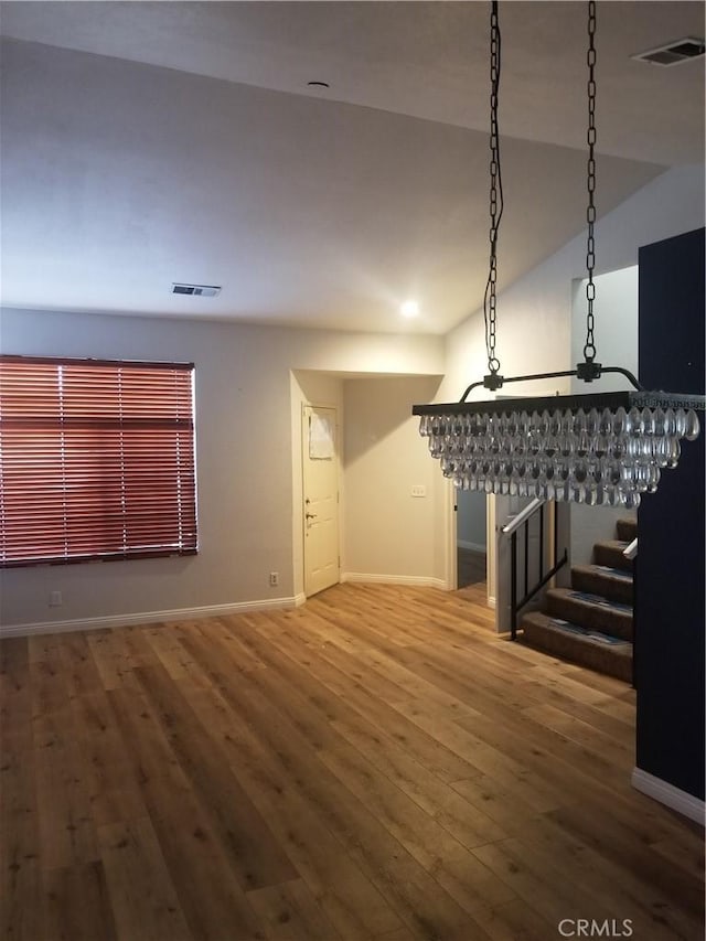 unfurnished living room featuring stairway, baseboards, hardwood / wood-style flooring, and visible vents