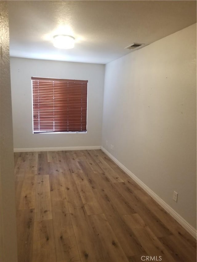 empty room featuring visible vents, baseboards, and wood finished floors