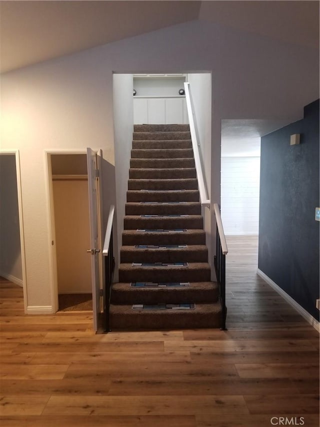 stairway featuring baseboards, vaulted ceiling, and wood finished floors