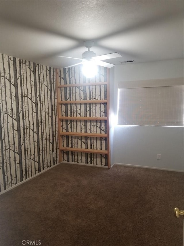 carpeted spare room with ceiling fan and visible vents