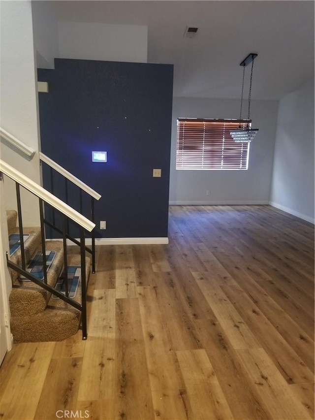 foyer with baseboards, stairs, wood finished floors, and visible vents