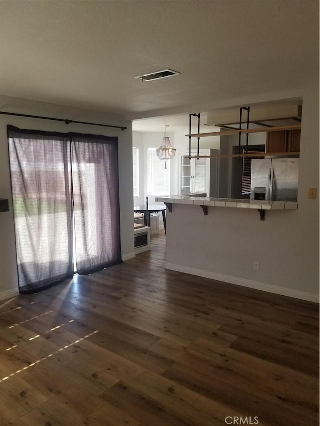 unfurnished living room featuring baseboards, dark wood-style flooring, and visible vents