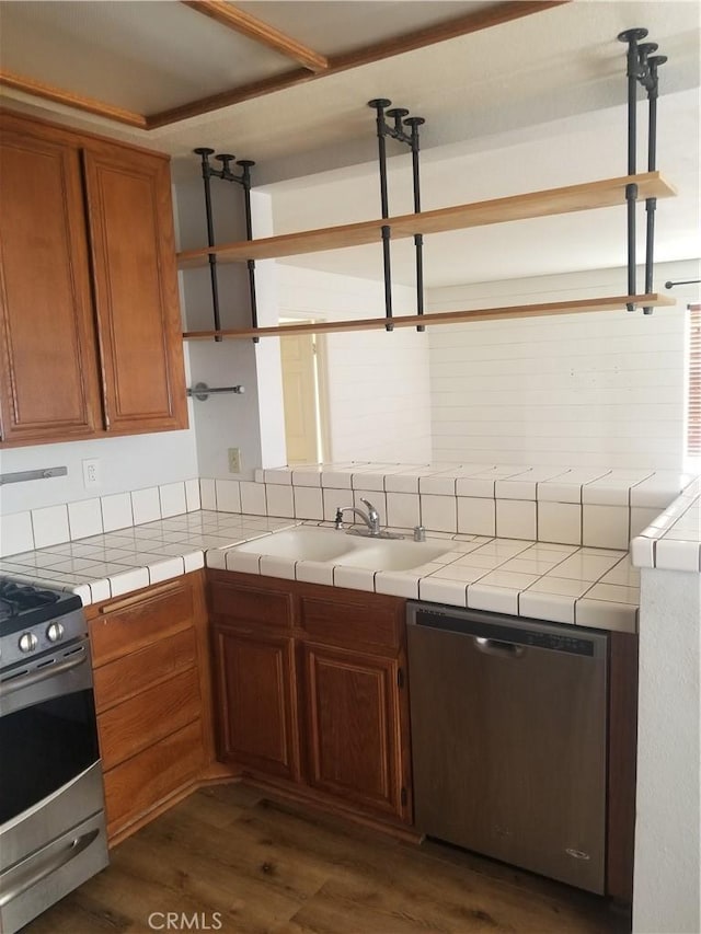 kitchen with tile counters, a sink, dark wood-style floors, and stainless steel appliances
