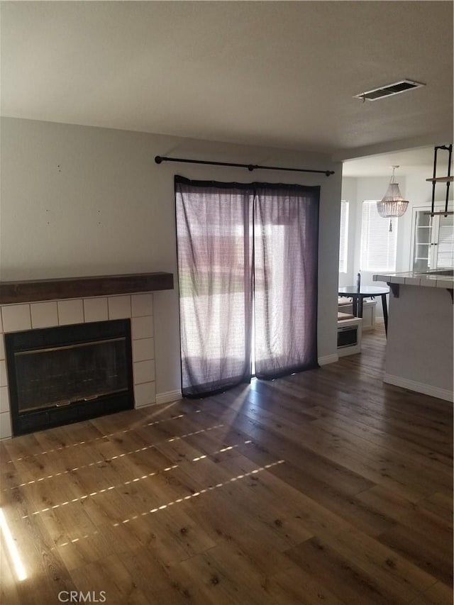 unfurnished living room featuring baseboards, visible vents, wood finished floors, and a fireplace