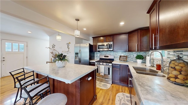 kitchen with decorative light fixtures, backsplash, a center island, sink, and stainless steel appliances