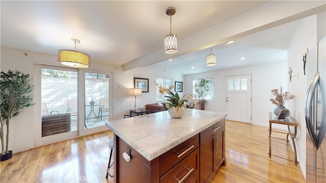 kitchen featuring a center island, beam ceiling, pendant lighting, light hardwood / wood-style flooring, and stainless steel fridge