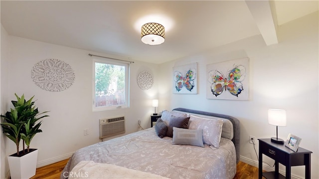 bedroom with a wall mounted AC and dark wood-type flooring