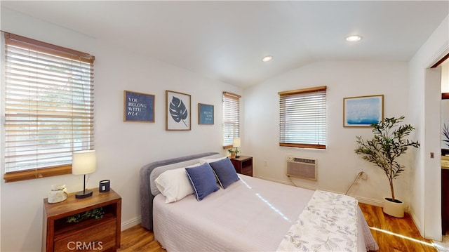 bedroom featuring lofted ceiling, a wall mounted AC, wood-type flooring, and multiple windows