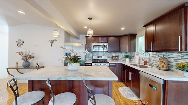 kitchen with stainless steel appliances, tasteful backsplash, decorative light fixtures, a kitchen island, and sink