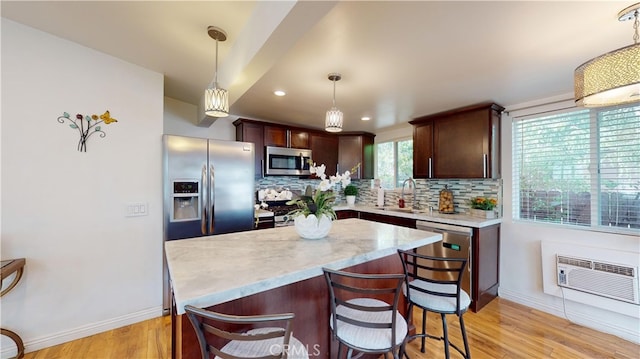 kitchen featuring pendant lighting, appliances with stainless steel finishes, tasteful backsplash, sink, and light hardwood / wood-style flooring