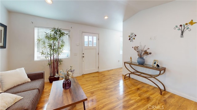 living room with vaulted ceiling, a wealth of natural light, and light hardwood / wood-style flooring