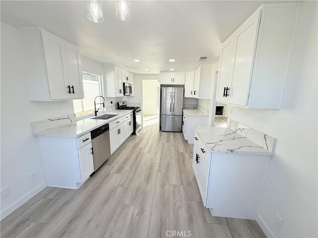 kitchen with light hardwood / wood-style floors, sink, hanging light fixtures, appliances with stainless steel finishes, and white cabinets