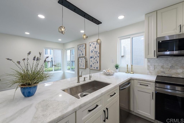 kitchen with sink, appliances with stainless steel finishes, light stone countertops, white cabinets, and decorative backsplash