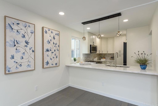 kitchen with hanging light fixtures, dark hardwood / wood-style floors, kitchen peninsula, white cabinets, and backsplash