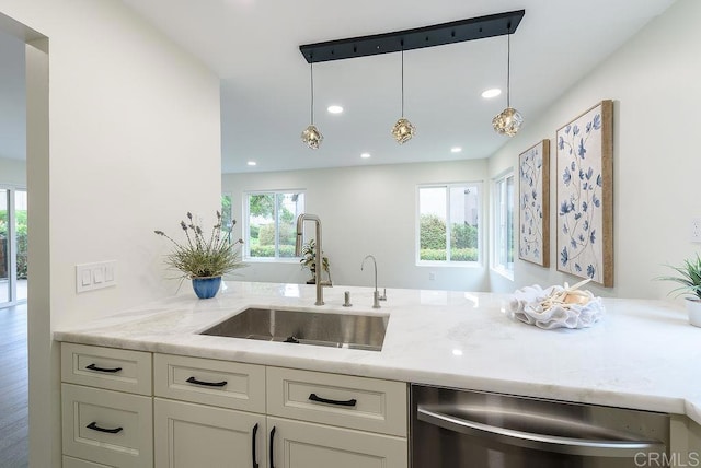 kitchen with pendant lighting, sink, light stone countertops, and dishwasher