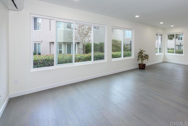 unfurnished room featuring recessed lighting, baseboards, dark wood-type flooring, and a wall mounted AC