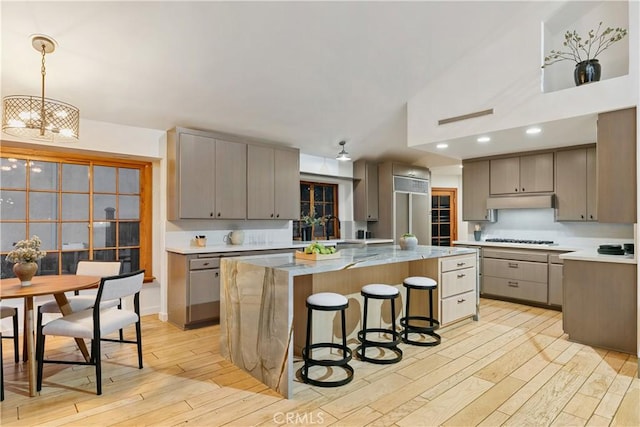 kitchen featuring gray cabinets, a chandelier, pendant lighting, light hardwood / wood-style flooring, and a center island